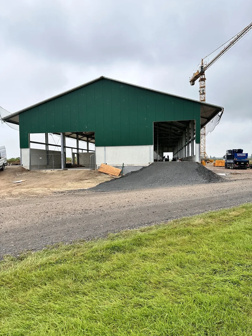 Eine Wissenschaftlerin und ein Wissenschaftler arbeiten hinter einer Glasfassade und mischen Chemikalien mit Großgeräten.